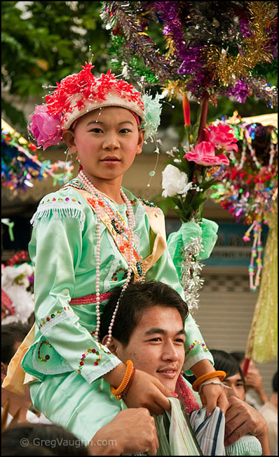 A Shan boy carried on his father's shoulders on way to becoming a monk