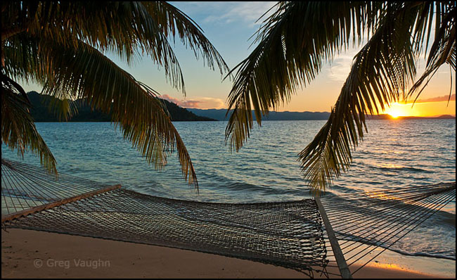 Hammock and palm trees on beach at sunset, Matangi Island, Fiji