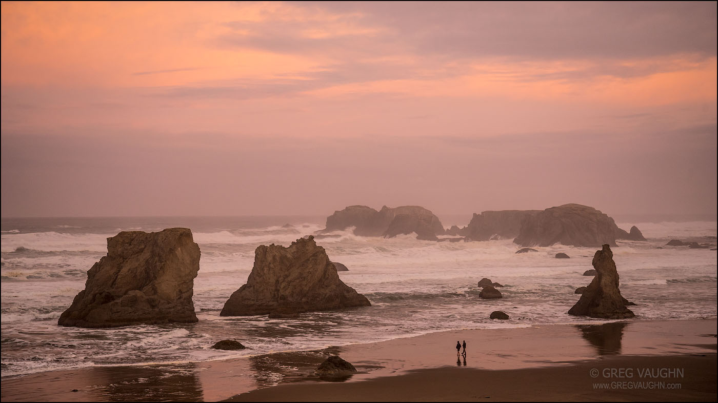 Two young men walking on Bandon Beach on a stormy dawn; Oregon Coast.