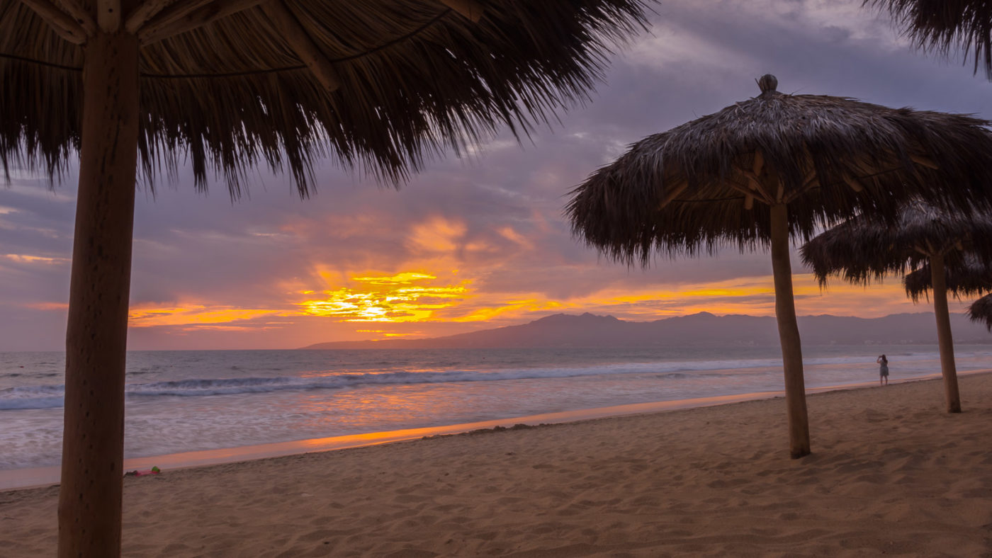 Palapas and people on the beach at sunset at Marival Resort, Nuevo Vallarta, Riviera Nayarit, Mexico.